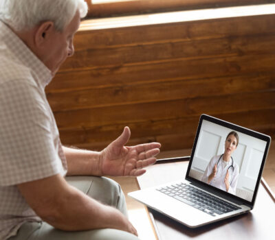 Fokussierter älterer 80er-Jahre-Patient, der sich über einen Computer-Videoanruf mit einem Arzt berät. Älterer Mann, der auf den Laptop-Bildschirm schaut und sich online mit einem Kardiologen unterhält, ältere Generation mit moderner Technologie.